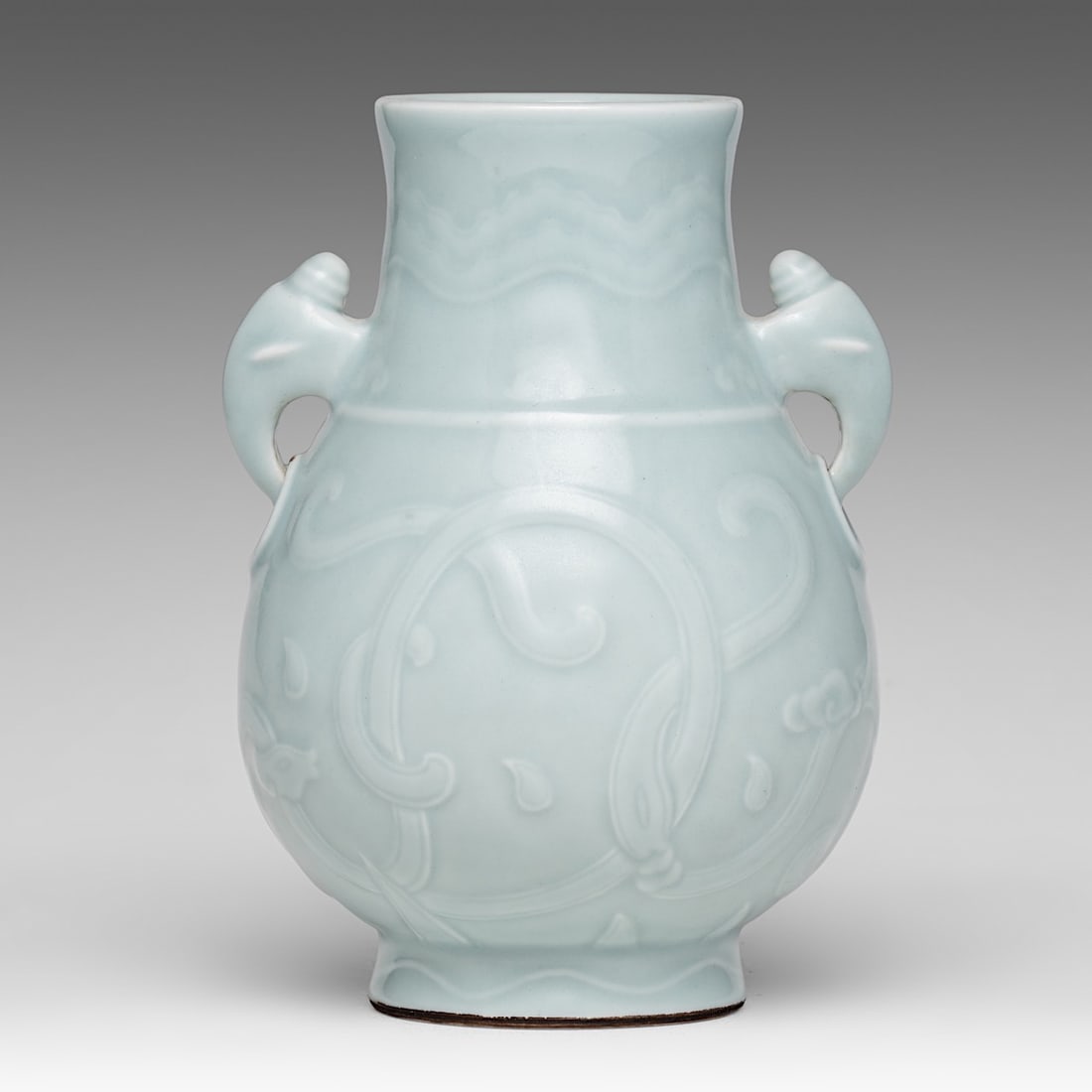 A Chinese carved celadon glazed hu vase, paired with mythical beast-head handles, with a Qianlong: A Chinese carved celadon glazed hu vase, paired with mythical beast-head handles, with a Qianlong mark, H 19,5 cmA Chinese celadon glazed hu vase, carved with archaistic motifs, paired with mythical b