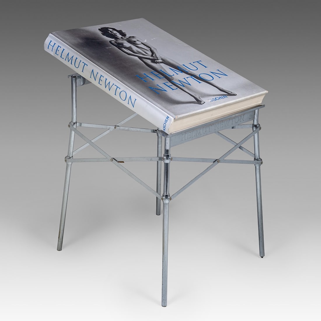 A Helmut Newton 'Sumo' book on stand, Taschen, 1999, signed and numbered: A Helmut Newton 'Sumo' book on stand, Taschen, 1999, signed and numberedThe stainless-steel bookstand is designed by Philippe Starck.Limited edition of 10,000 this being number 04326.H 71 - 51 cm (boo