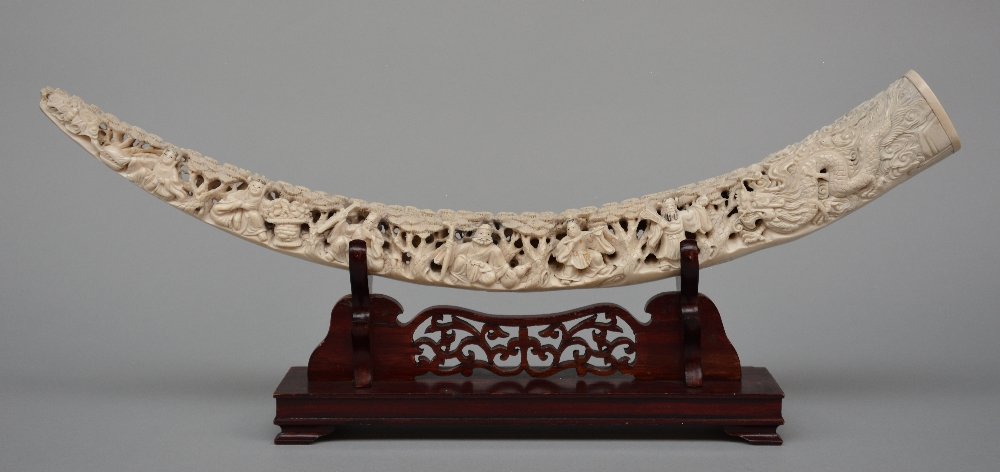 A Chinese ivory tusk carved with the Eight Immortals,: A Chinese ivory tusk carved with the Eight Immortals, on a matching wooden base, scrimschaw decorated, first half 20thC, L 60 cm, Weight: ca. 872 g (without base)