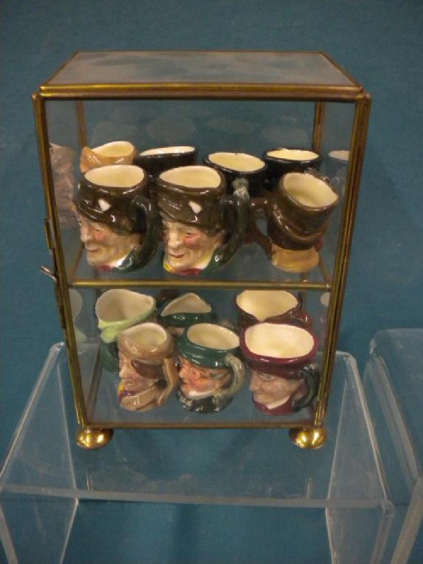 13 Royal Doulton Miniature Mugs: 13 Royal Doulton Miniature Mugs in brass and glass case, includes: (some duplicates), (2) Arry, (2) John Peal, (2) Paddy, Sairey Gamp, Auld Mac, Old Charley, Cardinal, Mr. Pickwick, Mr. Micamber and S