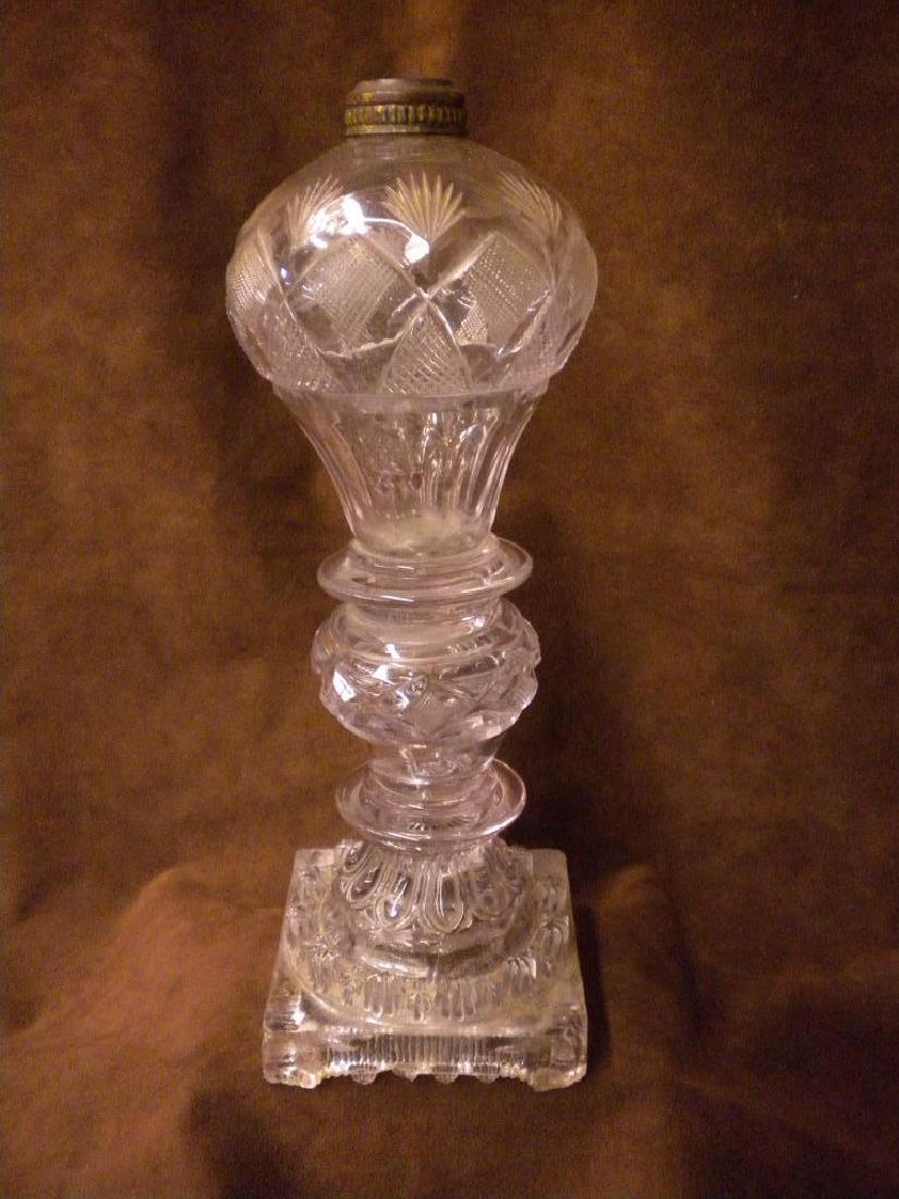 Sandwich Glass Whale Oil Lamp: Sandwich Glass Whale Oil Lamp, clear glass with fan and saw tooth cut font on an similar urn and ring column with raised foliate, design base upon a square footed platform, 19th C., 12"h. CONDITION: C