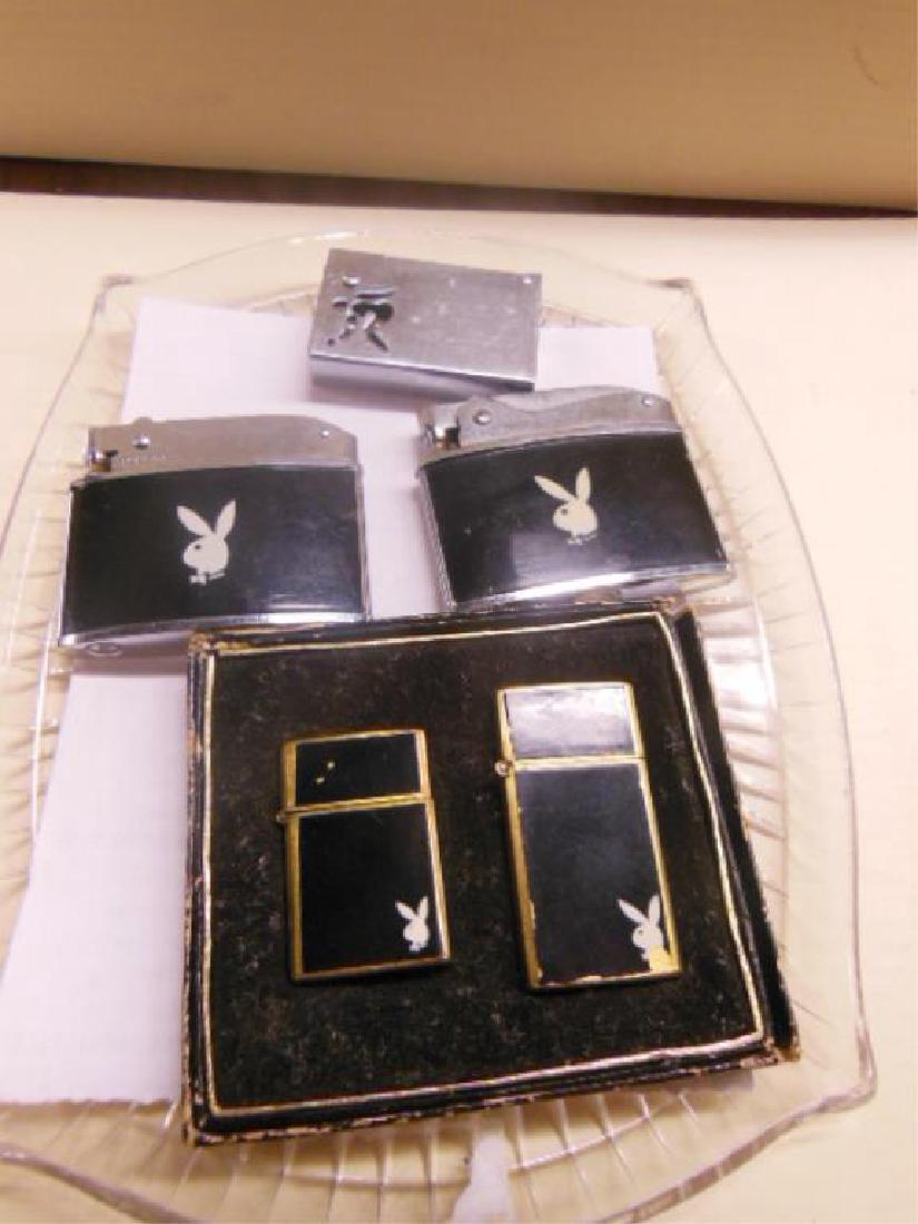 4 Playboy Pocket Lighters: 4 Playboy Pocket Lighters all with white "Playboy Bunny" symbol including 2 piece Minix lighter set (1 3/8" and 1 3/4"), in original box, and (2) other, 2 1/8", plus (1) lighter with open work "nude"