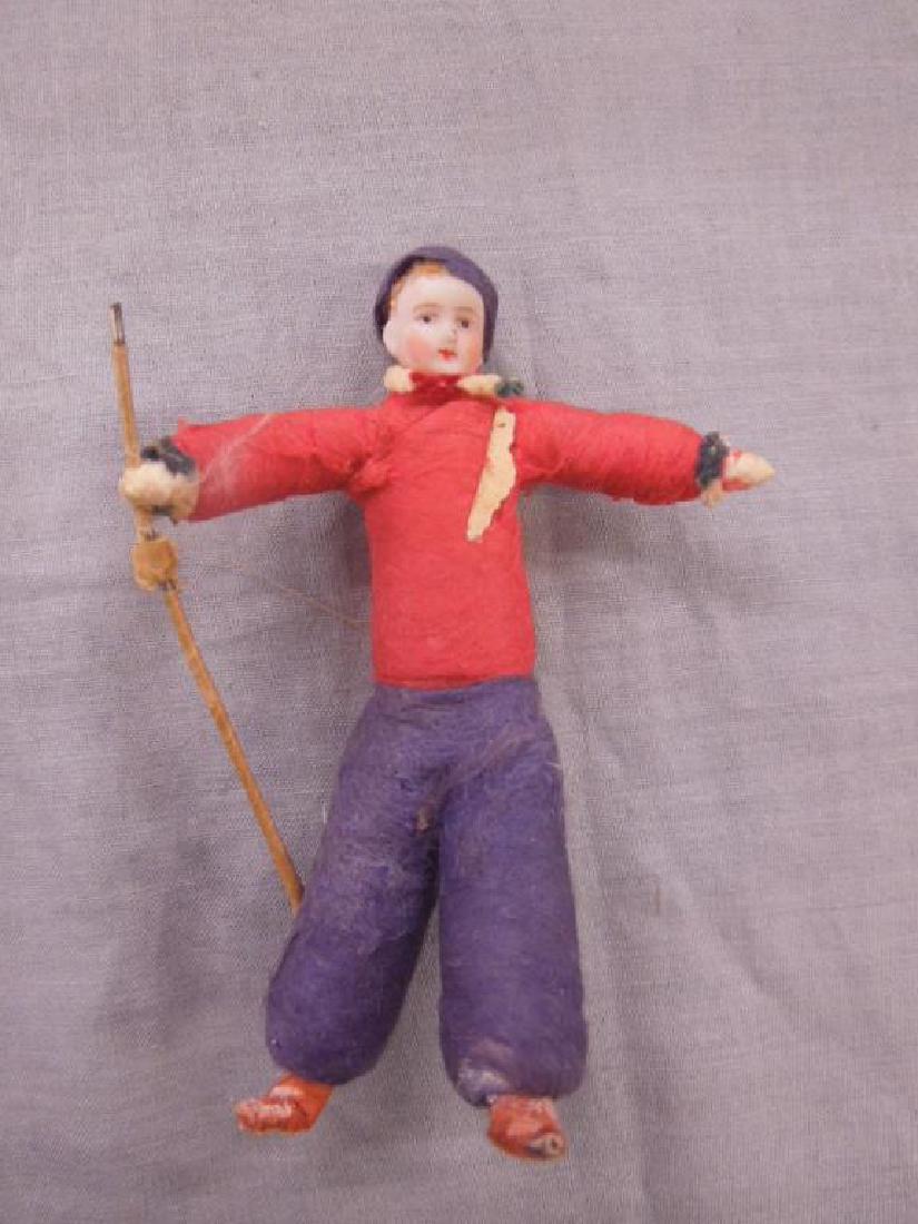 Vintage Bisque Figural Tree Ornament: Vintage Bisque Figural Tree Ornament, painted bisque head on red and blue cotton ski outfit body, clad metal ski pole, early 20th C, 4"h. CONDITION: Wear to extremities, paper and glue residue on left