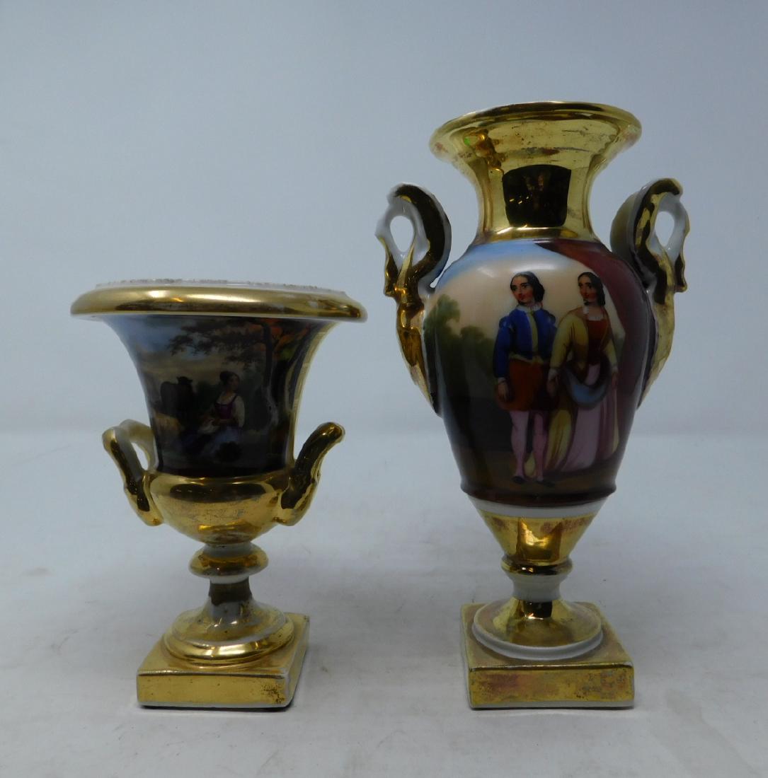 Two Old Paris Porcelain Bolted Urns: [2 items] Two Vieux Paris Porcelain bolted urns: a baluster-form vase with square foot and swan handles hand-painted with a courting couple on the observe and a landscape on the reverse, along with a 
