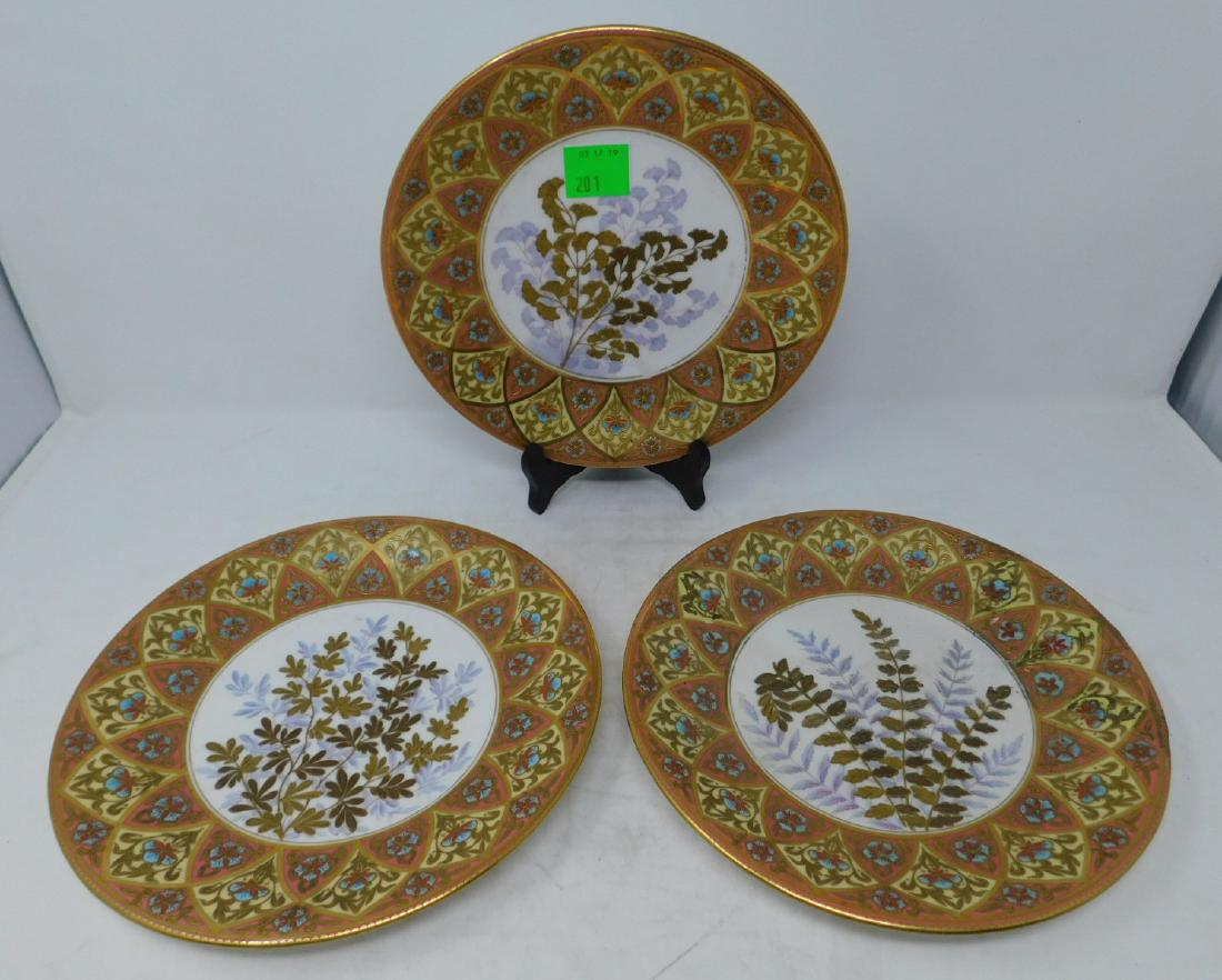 Three Royal Crown Derby Plates: Three Royal Crown Derby Plates, with elaborately hand-painted raised gold decoration in the Aesthetic style with a central spray of gingko leaves surrounded by a Gothic Revival influenced border in or