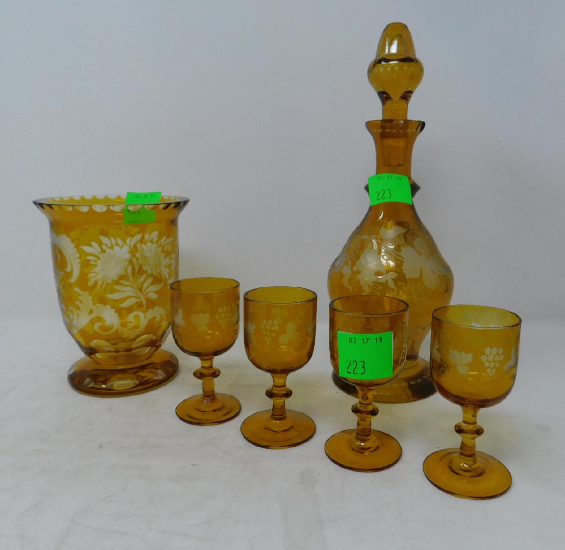 Bohemian Amber Cut to Clear Glass Lot: [6 items] Bohemian Amber Cut to Clear Glass Lot: a liquor decanter with four glasses, all in the grapevine pattern, along with a short, wide-mouthed, footed vase. Czech/Bohemian, mid-20th century. Pro