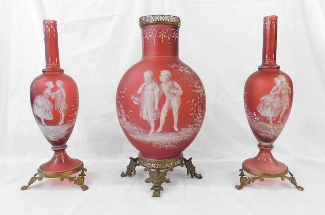 3 Pc Bohemian Mary Gregory Garniture Set: 3 Pc Bohemian Mary Gregory Garniture Set, satin finished ruby glass with white finished courting figures in garden landscape: brass fitted bases; includes: a pair of 13 1/4" bottle form vases and a 13