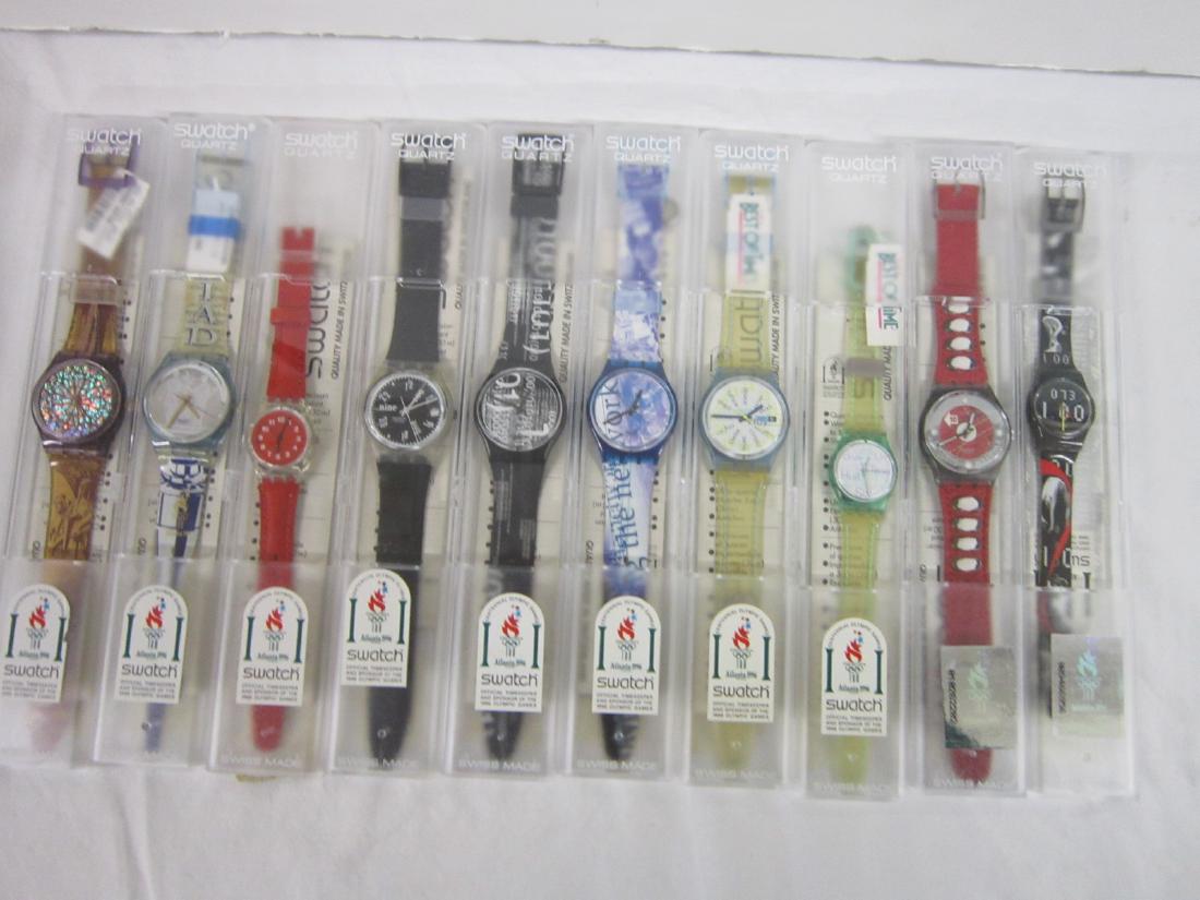 10 Swatch Watches In Original Cases: Ten Swatch Watches In Original Cases. Most new old stock, in hard plastic cases, all with 1996 Atlanta Olympic stickers with folded information sheets including: Black Jet, GK 406 ( with date); Coding