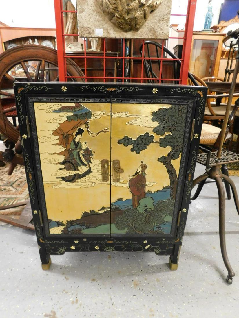Chinese Chinoiserie Cabinet: Chinese Chinoiserie Cabinet, black lacquered with gold and polychromed low relief carved floral and life scenes; two doors with interior shelf, late 20th C. CONDITION: Some edge and corner lacquer los