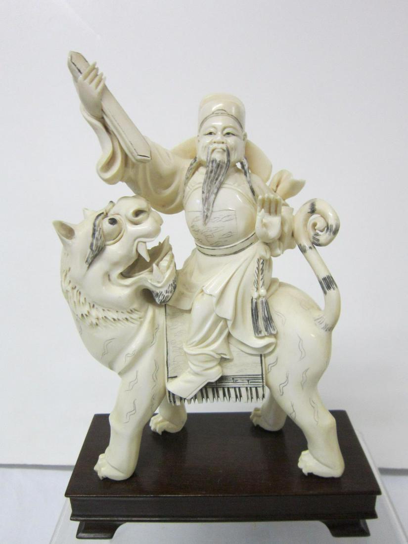 Chinese Sculpture: Chinese Sculpture, hand carved with inked highlights, depicts a nobleman riding upon a foo dog, wood base, early 20th C, overall 6" x 9" x 2 1/2". CONDITION: Very good, no issues identified.
