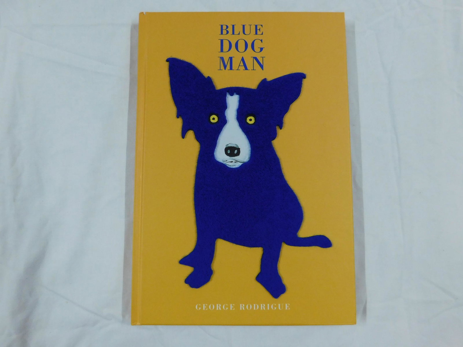 George Rodrigue Blue Dog Man Signed: Rodrigue, George, Blue Dog Man, Stewart Tabori & Chang, New York, 1999. Signed by the "Blue Dog" artist on the ffep. Fuzzy felt Blue Dog applique to front board. Laid in are Borders bookmark listing t