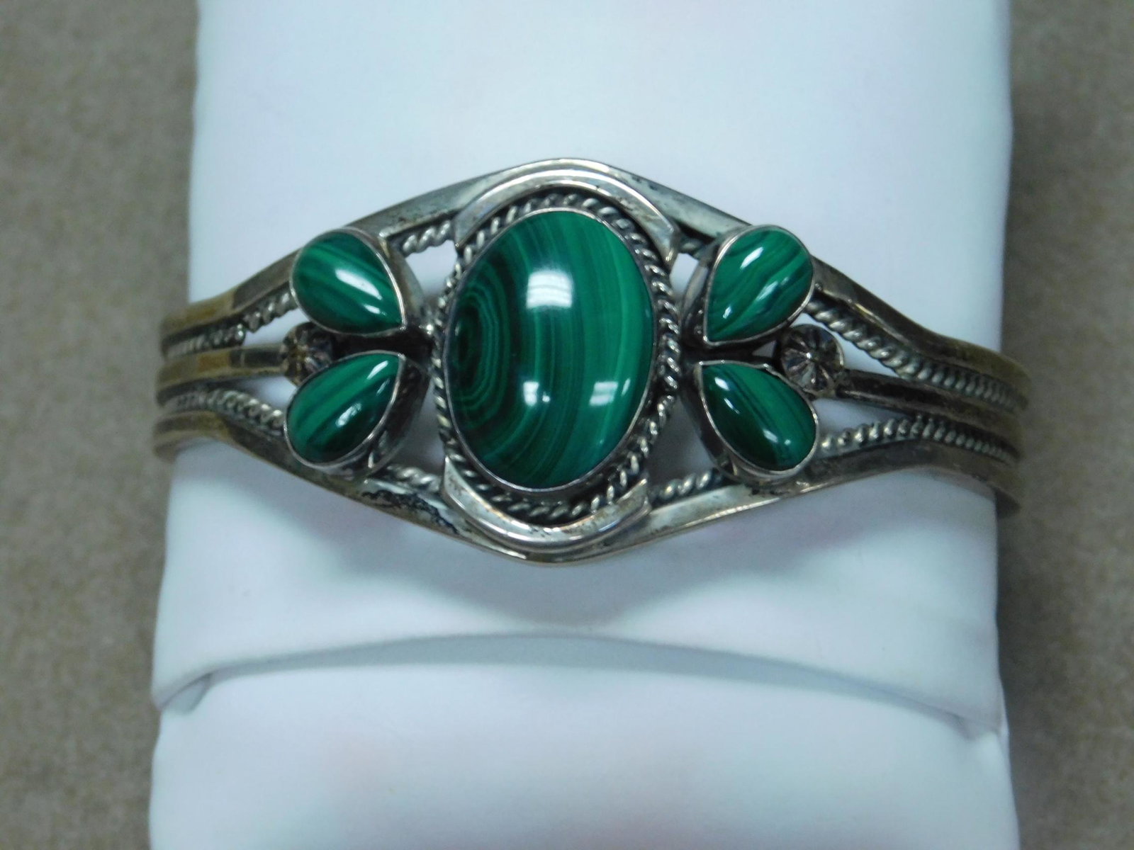 American Indian Cuff Bracelet: American Indian Cuff Bracelet, sterling, features five malachite cabochon oval and tear drop stones in bezel settings with rope and rosette embellishments, illegible makers name, interior diameter 2 1