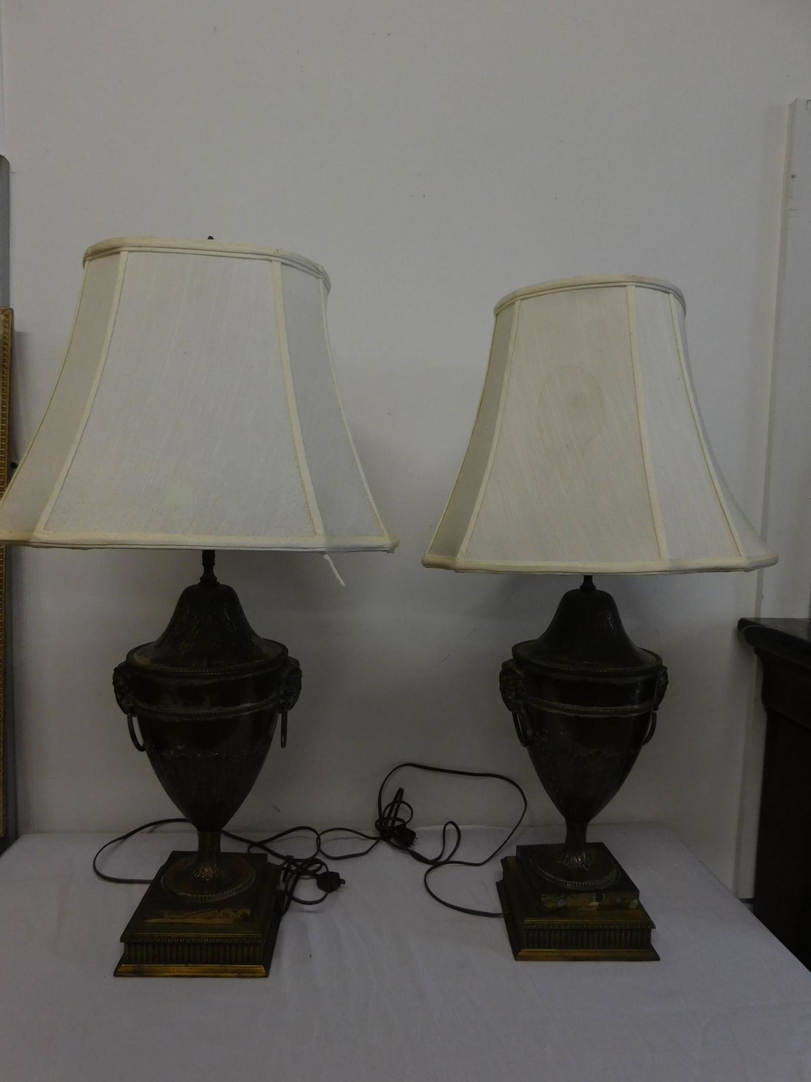 Pr Neo Classical Style Urn Lamps: Pr Neo Classical Style Urn Lamps, silver plate over copper, features acanthus embossing and applied ram's head handles wide ring drops, square base again upon a brass leaf cast square base, 19th / 20t