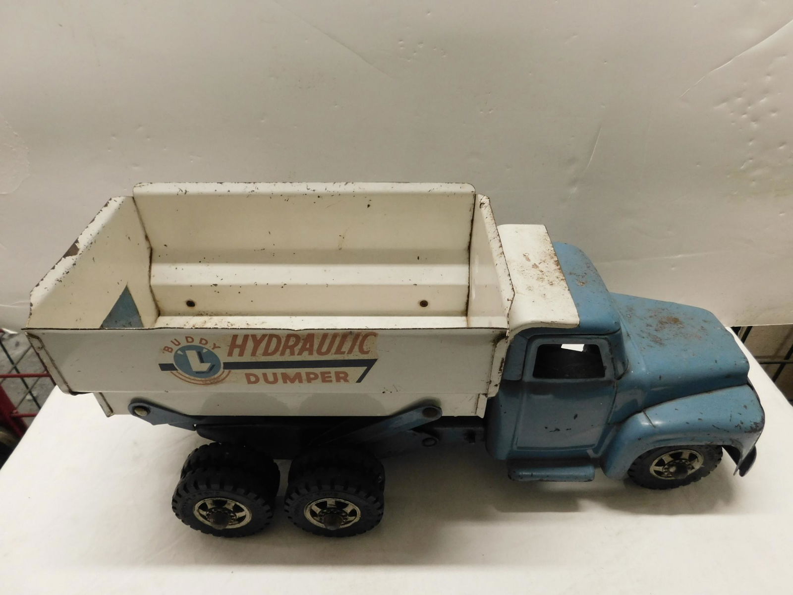 Vintage Buddy "L" Pressed Steel Dump Truck: Vintage Buddy "L" Pressed Steel Dump Truck, hydraulic dumper, blue cab and chassis, white hopper with lever release hydraulic piston under hopper, 20" overall length. CONDITION: Some paint loss and ve
