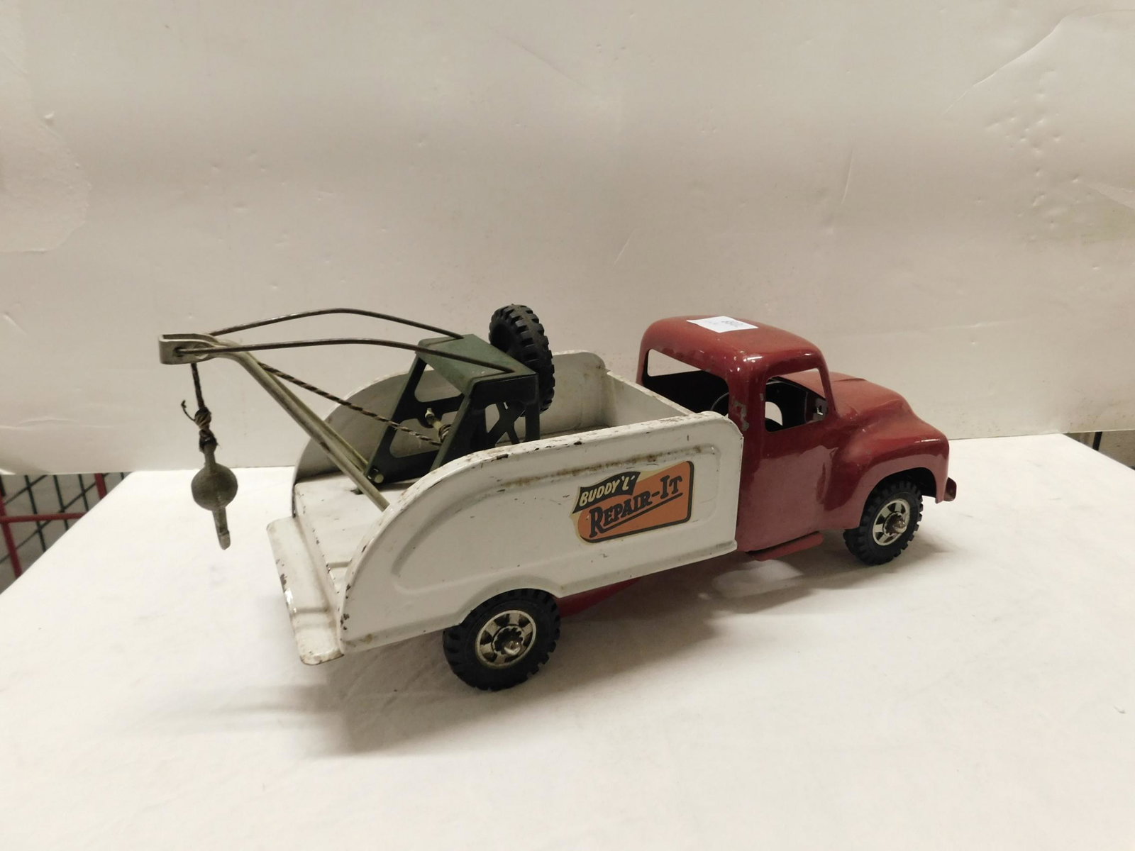 Vintage Buddy "L" Pressed Steel Tow Truck: Vintage Buddy "L" Pressed Steel Tow Truck, "Repair -It", red cab with white bed wheel crank(on side) wrecking ball with hook on string, hard rubber wheels, 16"l. CONDITION: Some paint loss and wear fr