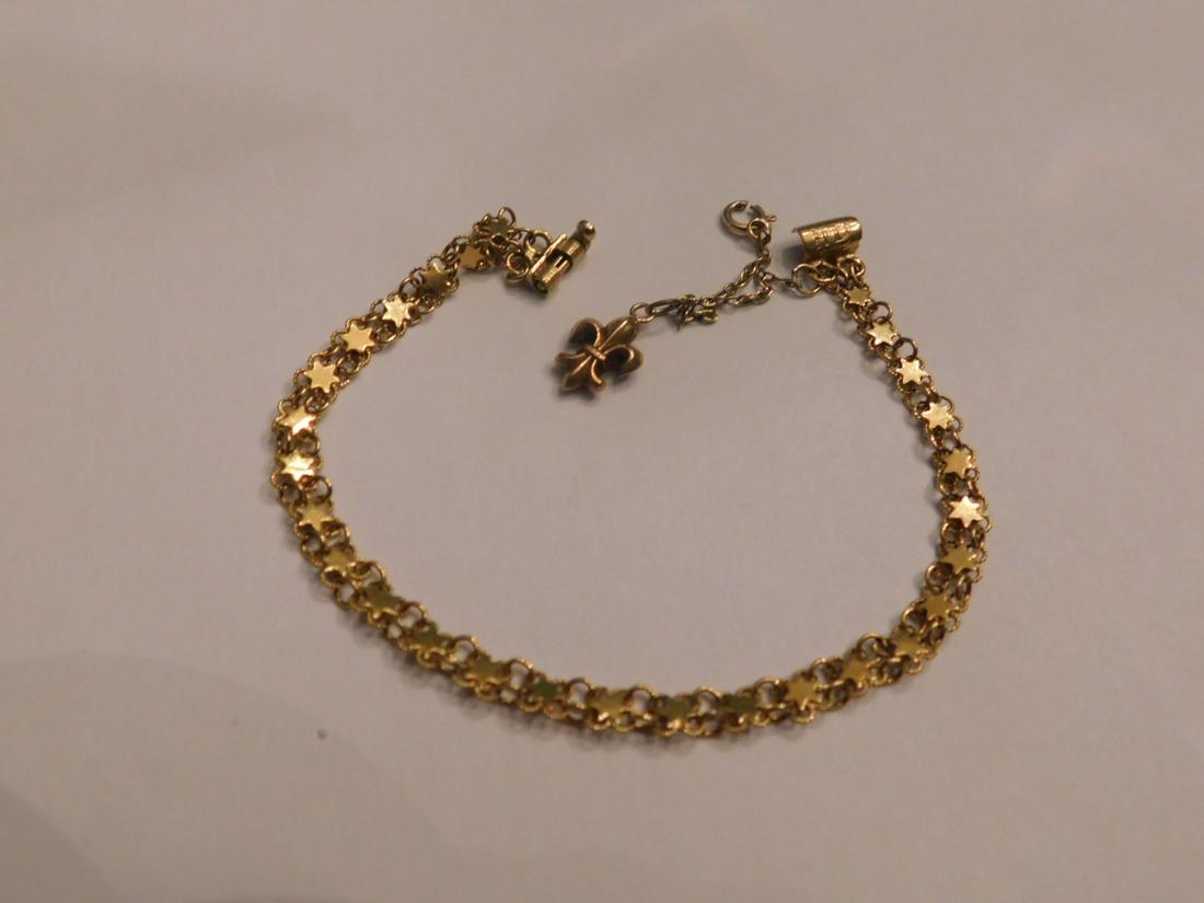 9k YG Star Link Bracelet: Gold Bracelet 9k y gold star and link bracelet with fleur de lis charm, on safety chain, bar clasp, length 7”, 4.3 DWT. [68d] CONDITION: No issues identified.