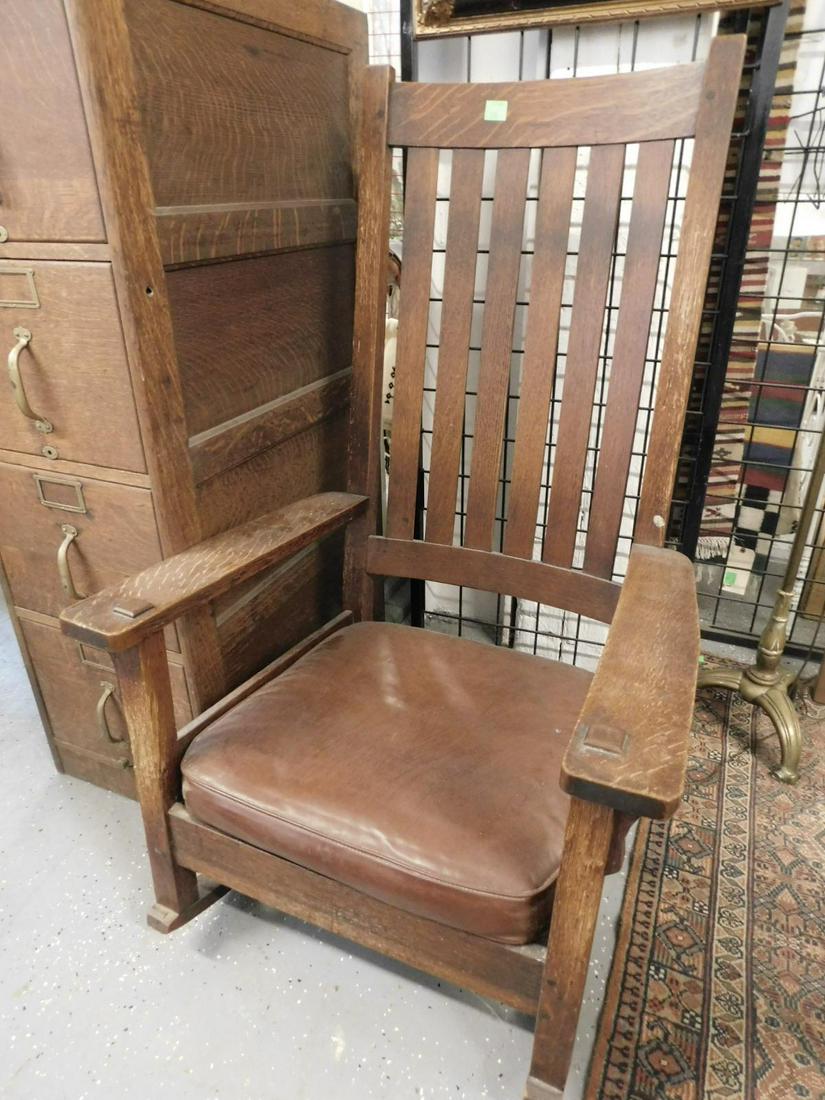 Arts & Craft Oak Rocker: Arts & Crafts Oak Rocker high slat back,l flat arms with through mortise, brown faux leather upholstered seat cushion, circa 1910-20, hgt 48 1/2" CONDITION: Very good, wear to back stiles.