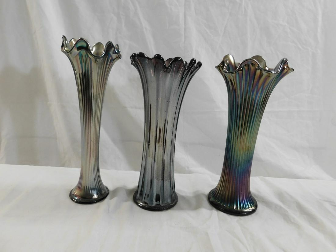 Three Ribbed Carnival Glass Swung Vases: Three Ribbed Carnival Glass Swung Vases, consisting of a Fenton Fine Rib in blue, a Westmoreland Corinth in purple, and a Northwood Fine Rib in purple. Size: tallest is 10.25". CONDITION: wear to bott