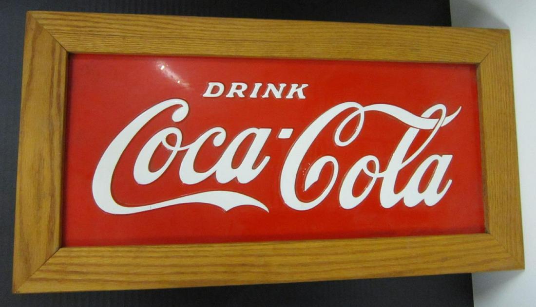 Framed Coca Cola Metal Sign: Framed Coca Cola Metal Sign, red with white painted raised letters "Drink Coca-Cola", 9 1/4" x 21 1/2" (site) in a 13 1/4" x 25 1/2" oak frame. CONDITION: Minor line paint loss on L and bottom of firs
