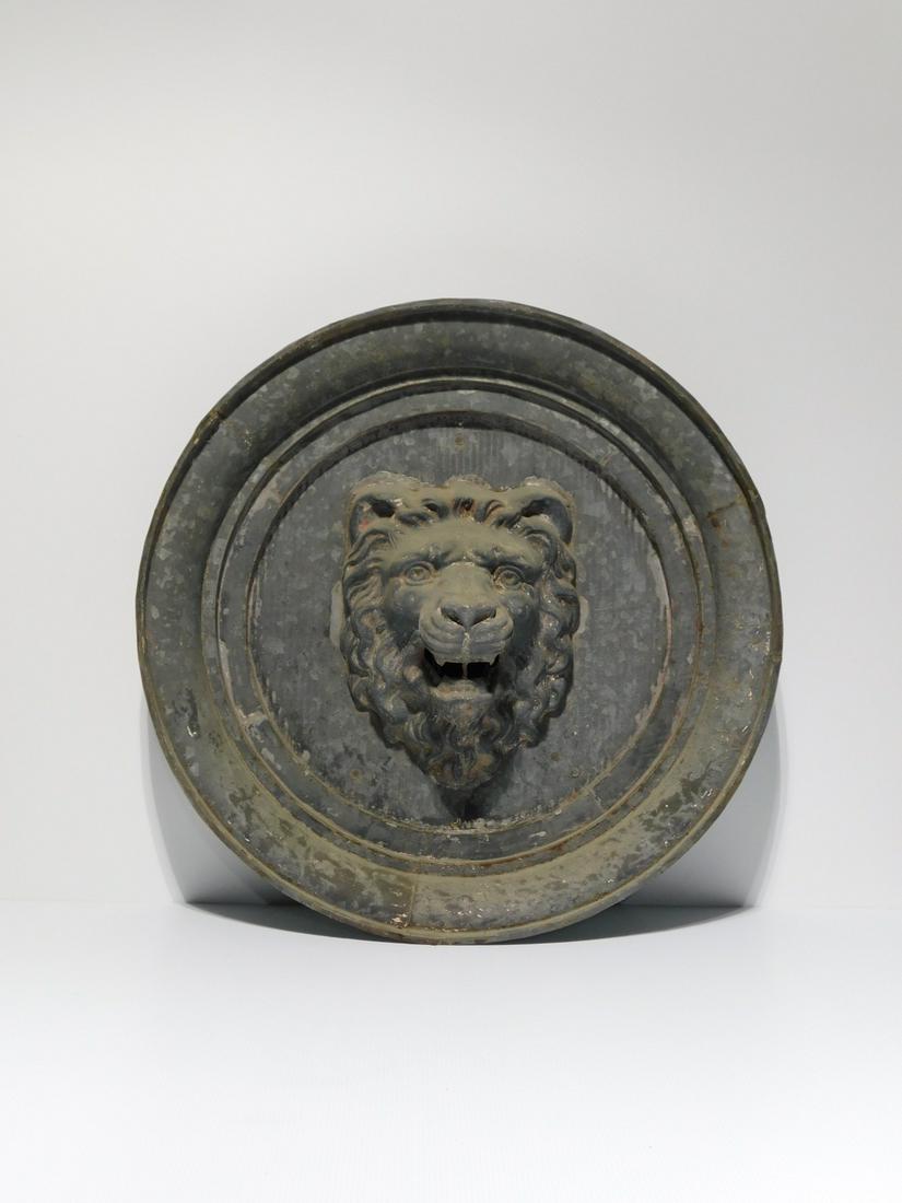 Pressed Metal Architectural Lion Medallion: Pressed Metal Architectural Lion Medallion. A large pressed galvanized metal medallion with a molded edge with a lion's mask in the center. Clearly a piece of architectural salvage, likely from a buil