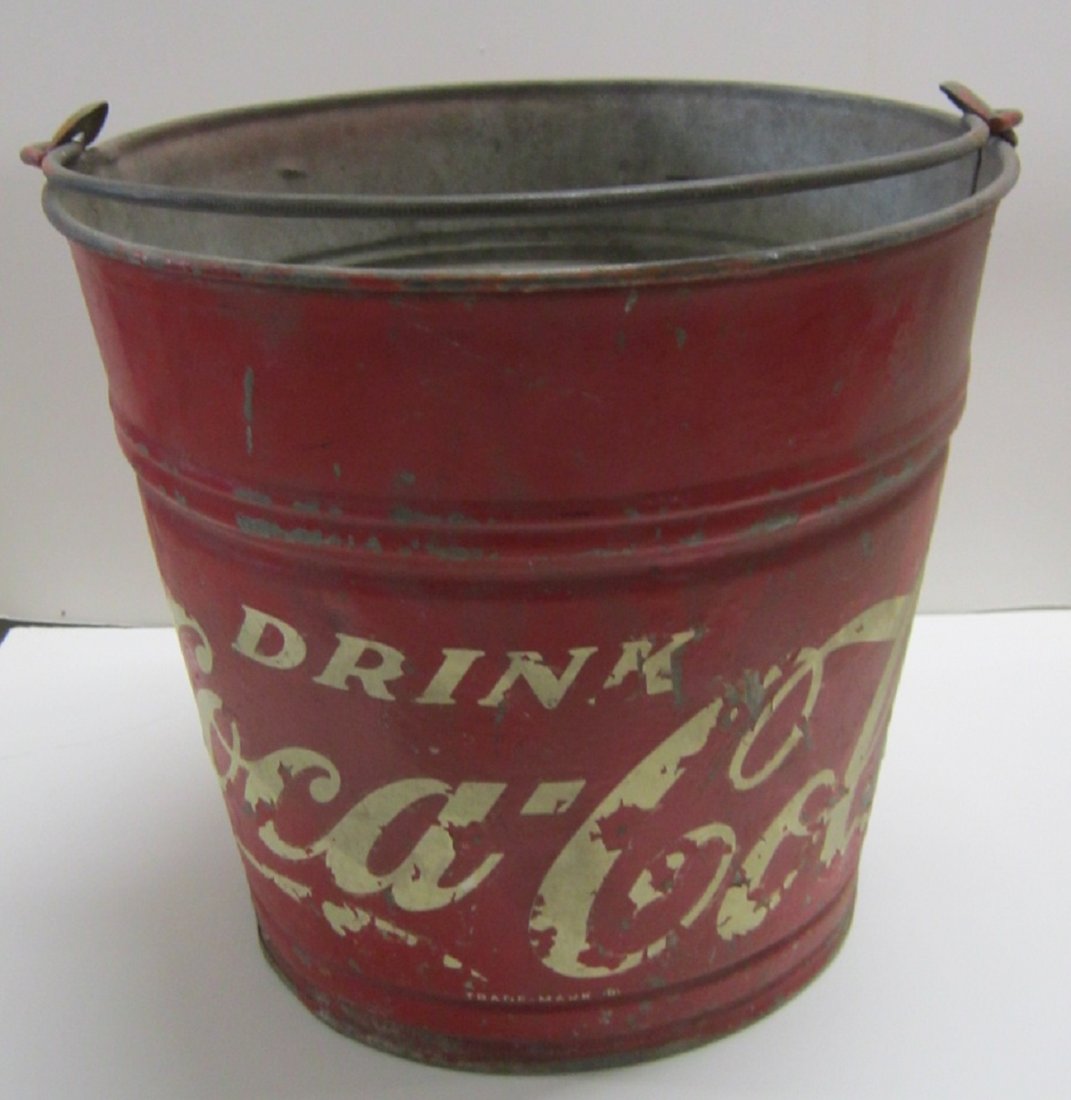 Vintage Coca Cola Water Bucket: Vintage Coca Cola Water Bucket, red paint with white decal lettering over galvanized metal, with rod form wire handle, 9" dia. (at bottom), 11" dia. (at top), 10" h. Condition; letter decal loss throu