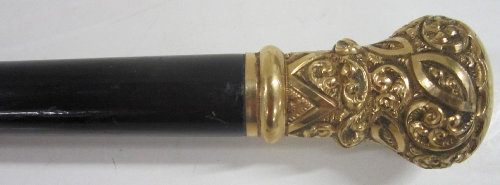 Gold & Ebonized Wood Walking Stick: Gold & Ebonized Wood Walking Stick, 10k. yellow gold repousse and engraved knob top with intricate scroll work designs, (no markings - tested), ebonized tapered shaft with nickled brass and steel ferr