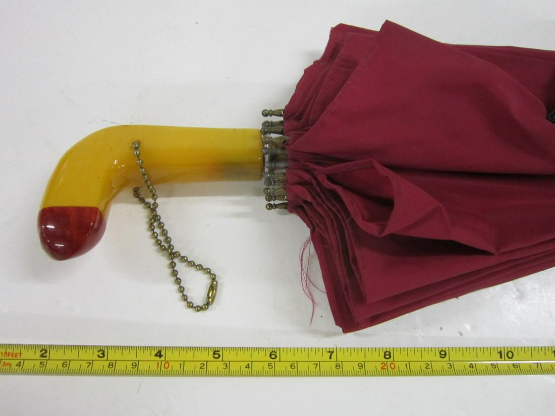 Art Deco Bakelite-Handled Parasol: Art Deco Bakelite-Handled Parasol, carmel-colored bakelite crook handle with cherry red tip; red cloth cover. Early 20th c. size: handle 4" l. parasol 23 1/2" l. [1F] CONDITION: A few pinholes in the 