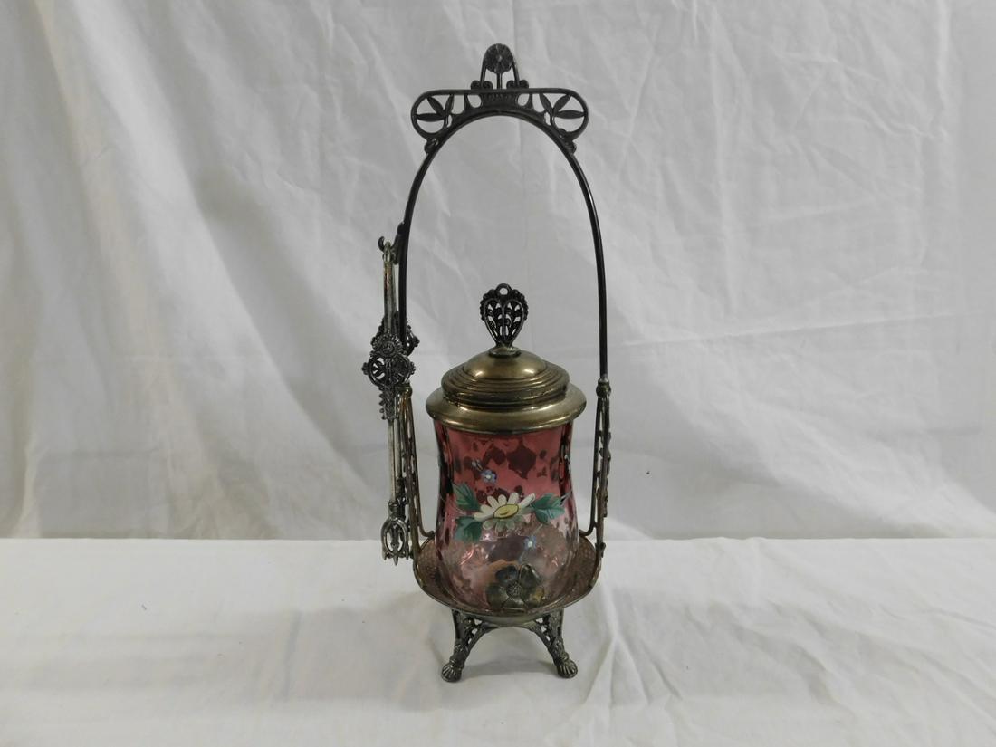 Victorian Pickle Caster: Victorian Pickle Caster, cranberry to clear glass caster with enameled floral band, rests in a Pairpoint quadruple plate stand with open work flowers, plus tongs, 13"h, circa 1880-1890. CONDITION: Ver
