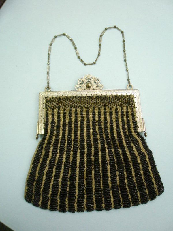 Vintage Beaded Purse: Vintage beaded purse w/knitted vertical rows of black beads, plated brass chaised frame floral & scroll design w/fancy closure & chain handle. Black cloth lining good condition. 5" x 7".