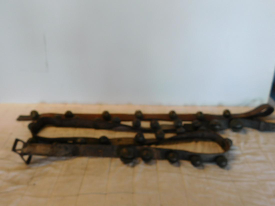 2 Sets of Older Horse Jingle Bells: Two Sets of Older Horse Jingle Bells including: one with seven 1 1/4" bells on a 39 1/2" leather strap and one with twenty-five 1 1/2" - 2 1/4" bells on a 90+" leather belt, all bells etched. CONDITIO