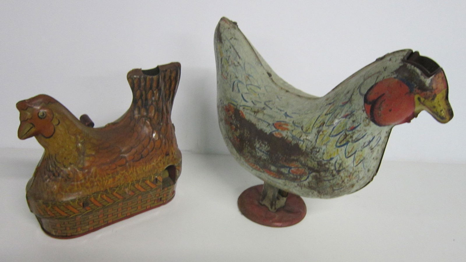 2 Tin Litho Egg Laying Chickens: Two Tin Litho Egg Laying Chickens including: Baldwin Mfg. Co with side noise making winder, 5 1/2" x 4 3/4" h and Wyandotte Toys with plunger style base, 8 1/4" x 7"h, No EGGS. CONDITION: Larger chick