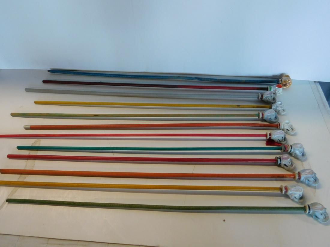 12 Vintage Porcelain Elephant Head Carnival Canes: Twelve Vintage Porcelain Elephant Head Carnival Canes, some glossy, some flat, all hand painted, 2" - 2 1/4" cane heads on wood sticks, 34" - 36", all trunks "Up". CONDITION: Some paint loss to wood s