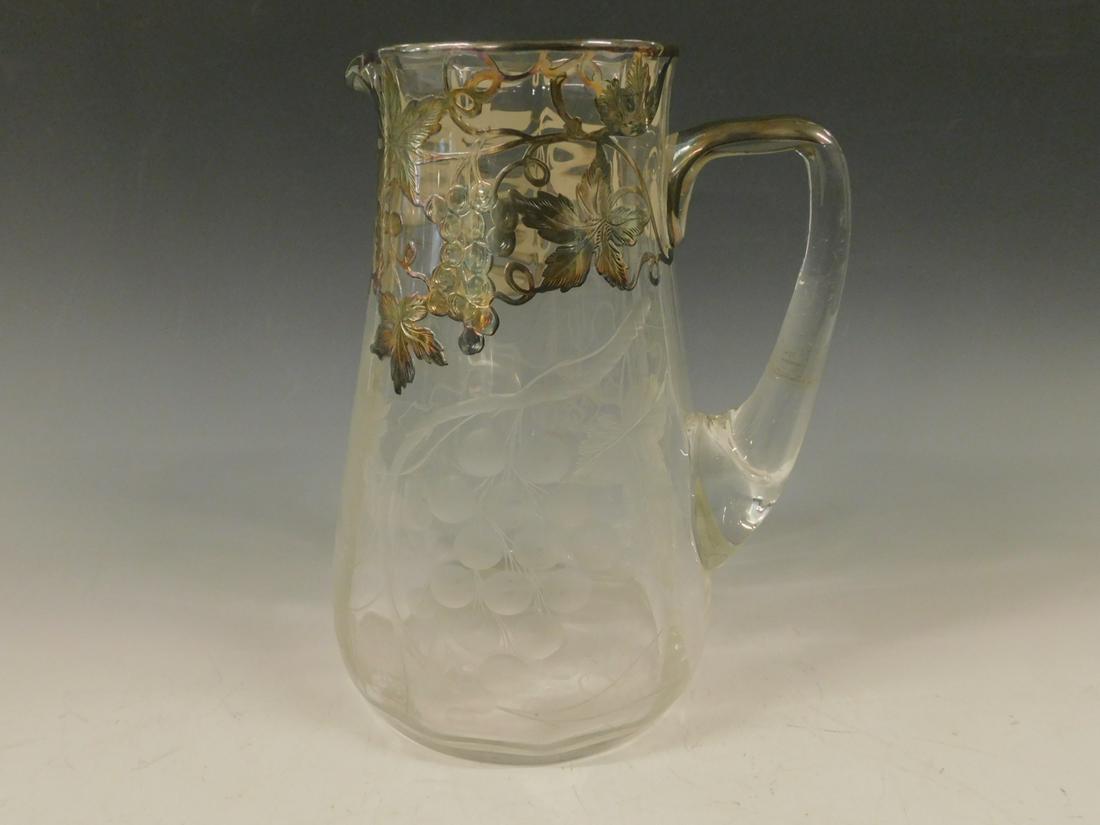 Silver Overlay Pitcher: Silver Overlay Pitcher, clear crystal with Intaglio etched grape / leaf clusters and matching sterling silver overlays at top rim, hand blown, early 20th C, 8 3/4"h. CONDITION: Very fine, no issues id