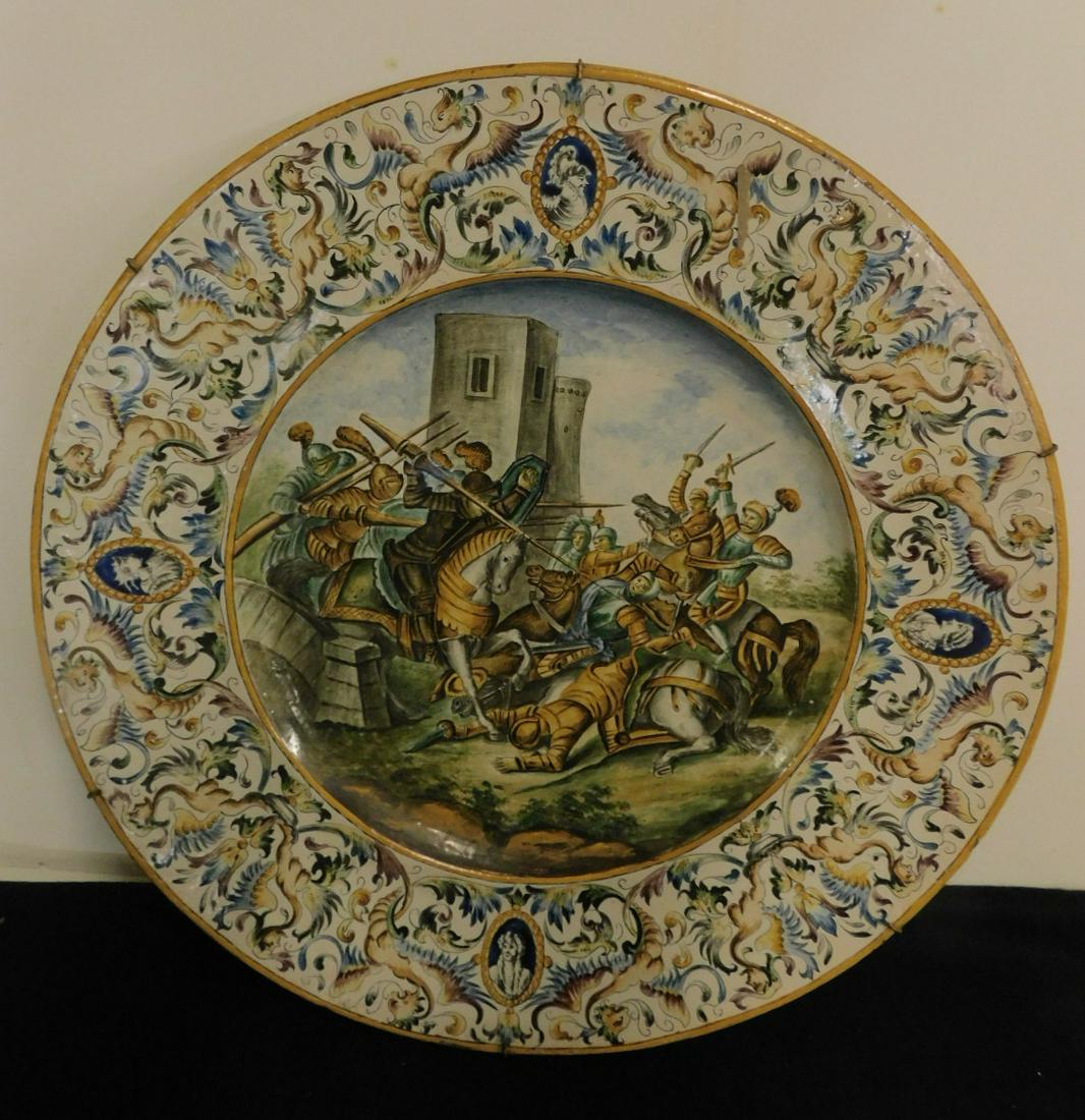 G(aetano) Battaglia Faience Pottery Charger: G(aetano) Battaglia Faience Pottery Charger, Italian, signed on reverse, 24 1/4" diameter, center panel depicts a battle scene with armored figures on horseback, castle in far ground, wide border of c