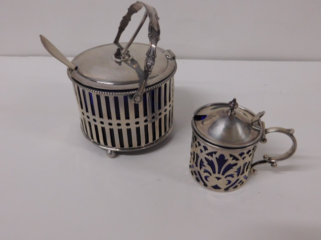 2 Sterling & Cobalt Glass Condiment Servers: Two Sterling & Cobalt Glass Condiment Servers includes: J. E. Caldwell & Co. hinged top with handle on a bar and circle, pierced body with ball feet and spoon, 4"d, 4 3/4"h, and a small hinged finial 