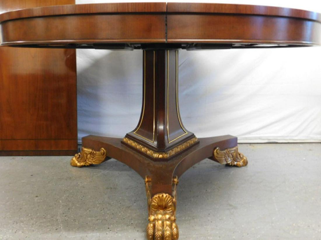 Baker French Empire Style Dining Room Table: Baker French Empire Style Dining Room Table, mahogany round 54"d table with band and line inlays, and one leaf three sided pedestal base with gilt winged claw feet, 20th C, includes: one 20" leaf. CON