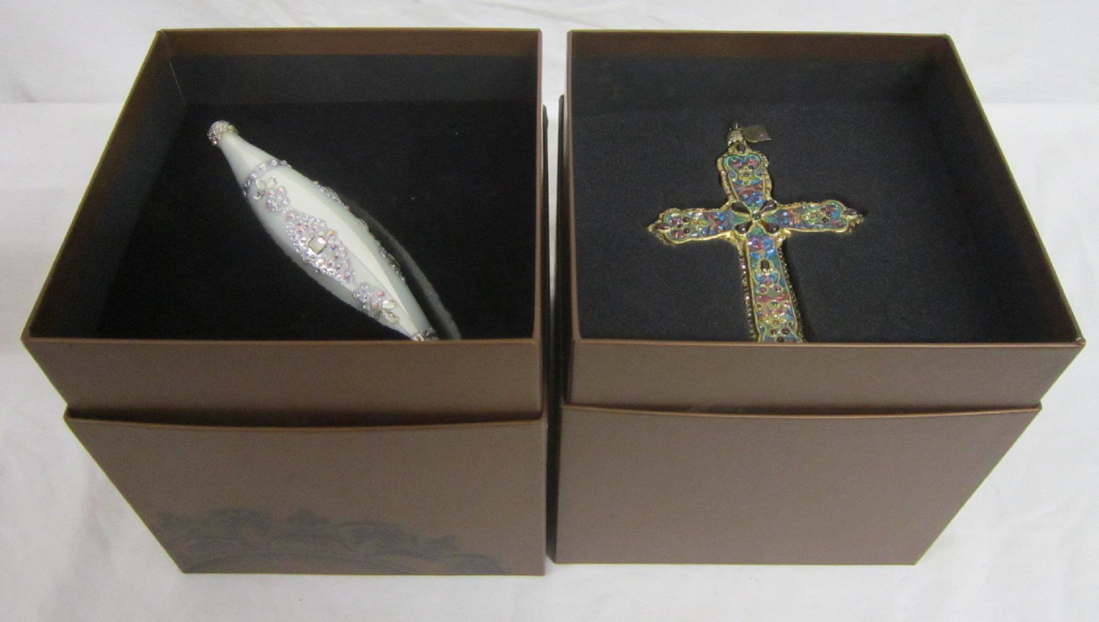 2 Jay Strongwater Christmas Ornaments: Two Jay Strongwater Christmas Ornaments includes: Cross form with enamel, gilt and jewels, 5 1/2" x 4 1/8", in original fitted box and an opalescent iridescent glass with applied jewels, length 7 1/8"