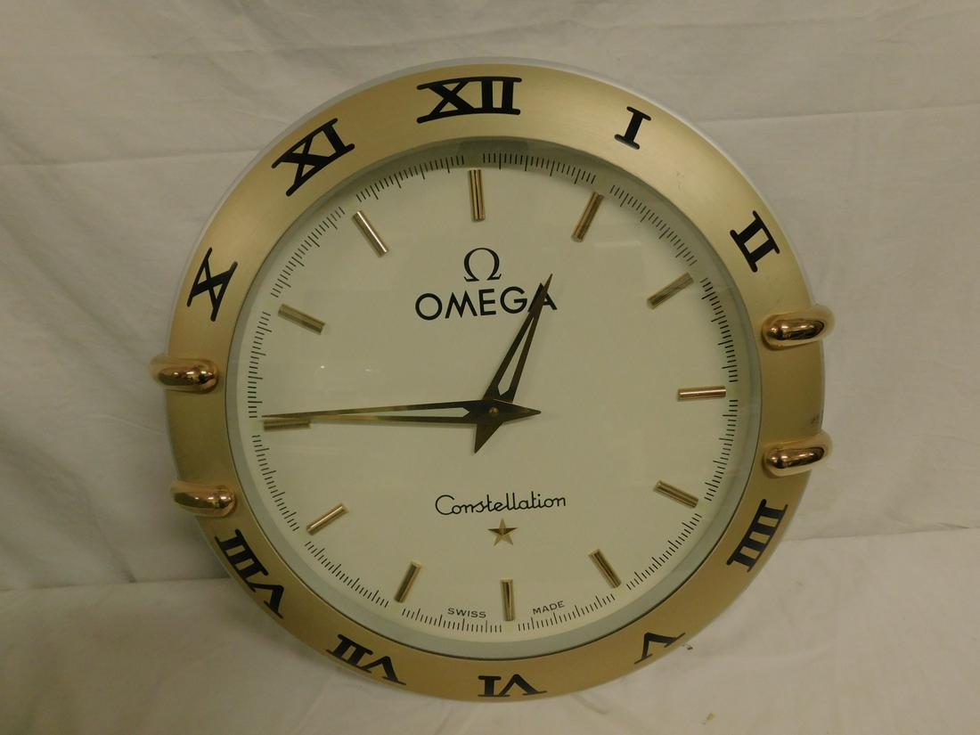 Omega Store Clock: Omega Store Clock, gold and silver finish brushed aluminum with polished gilt accents, Constellation model, Swiss made, W. German quartz movement, 21"d. CONDITION: Very good, minor wear along rim, cur