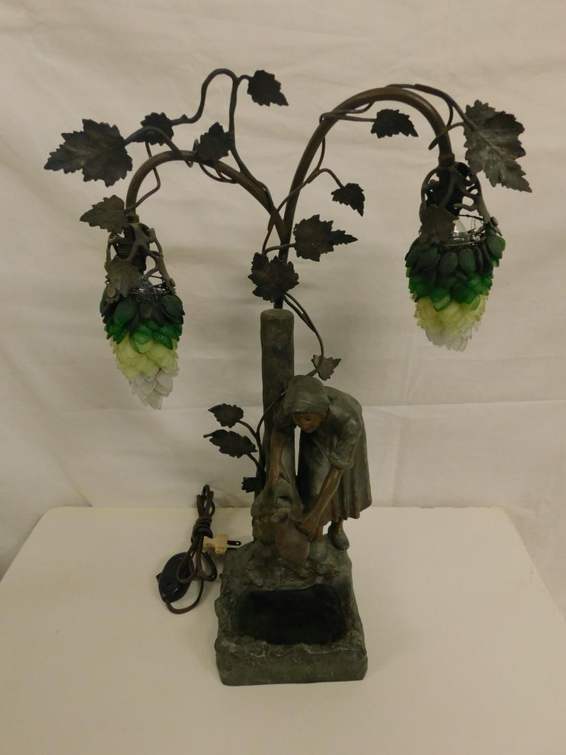 Figural Sculptured Night Lamp: Figural Sculptured Night Lamp, bronze patina spelter metal, depicts a maiden filling a jug at a water pump with a green slag glass pond below, grape vines run up column and support twin glass leaf clu