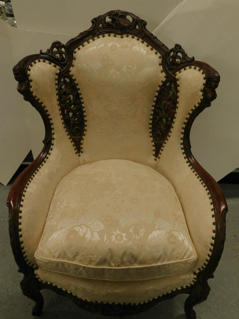 Fancy Carved Gentleman's Arm Chair: Fancy Carved Gentleman's Arm Chair, mahogany frame with female nude, music instruments, dragons, foliate and scroll carvings, some reticulated; pale peach floral brocade upholstery, early to mid 20th