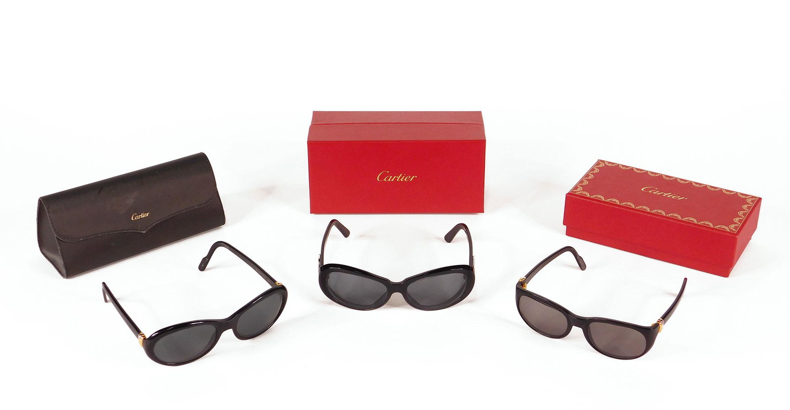 Cartier: Three Pairs Sunglasses: Three pairs Cartier sunglasses. Two pairs black frames with gold and silver accents, in Cartier cases; and one pair black with silver accents, number 4596164, in original case and box. Along with one 