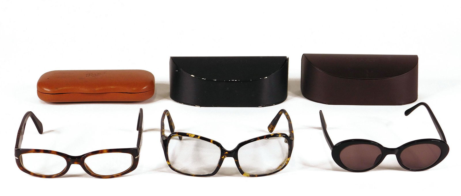 Oliver Peoples, Persol: Three Pairs Eye and Sungla: Three pairs glasses, comprised of one pair Oliver Peoples black sunglasses, one pair Oliver Peoples tortoiseshell style eyeglasses, and one pair Person tortoiseshell style eyeglasses. All in original