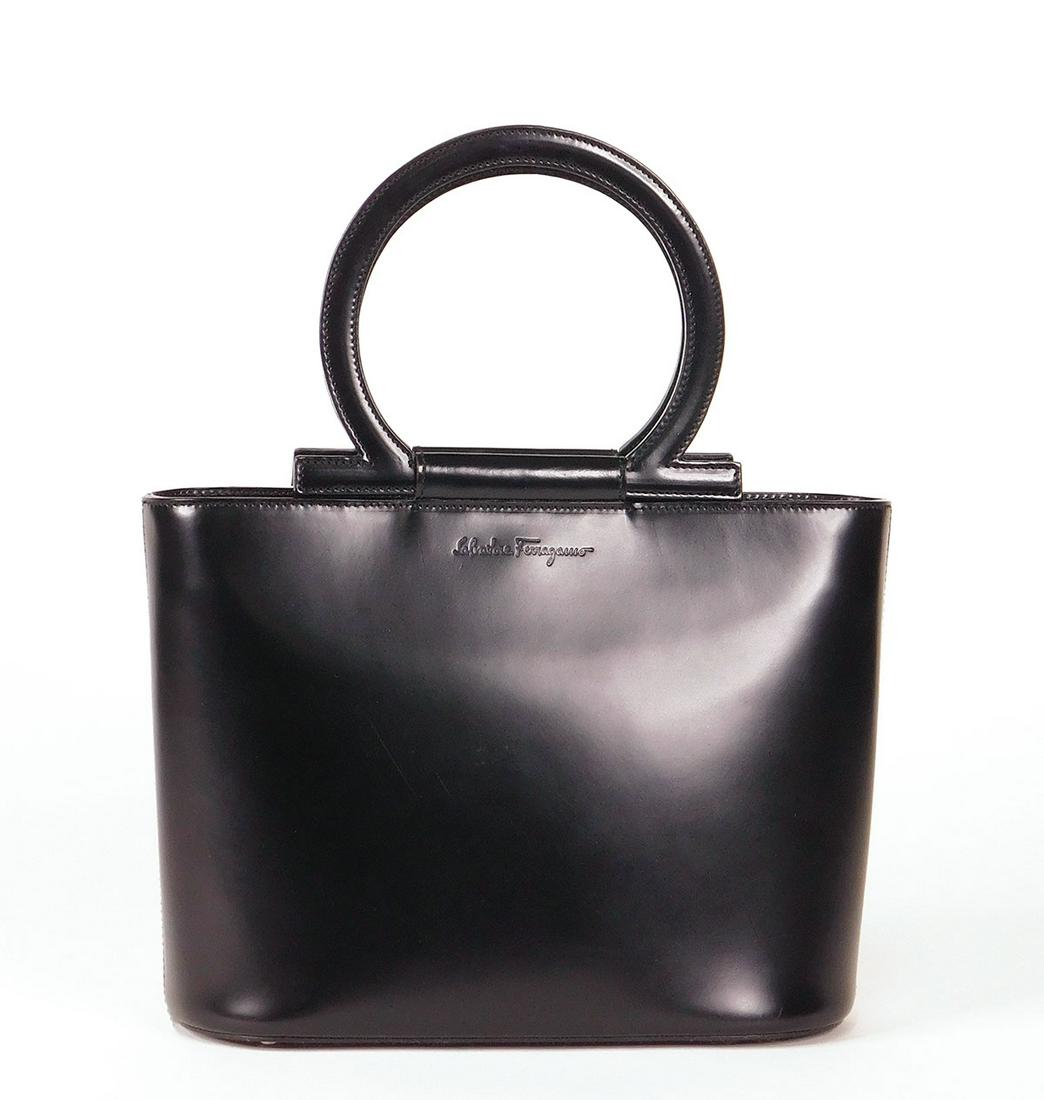 Salvatore Ferragamo Black Leather Bag: A Salvatore Ferragamo black leather tote handbag, DV-21 1344, with rigid loop handles and a magnetic flap closure. Red suede interior with one zippered pocket, polished chrome stud feet. With dustbag
