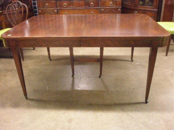 Hepplewhite Style Mahogany Dining Table: Hepplewhite style inlaid mahogany ovolo-end extension dining table (w/ two leaves), nicely grained top and apron, band and string inlay, tapered legs. American early 20th C. 30"=H; (65 1/2=h Closed) 4