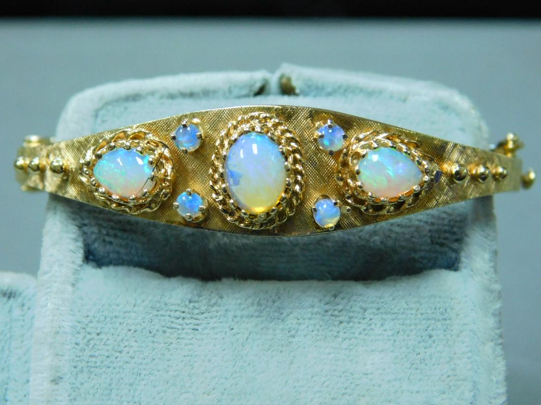 14k YG & Opal Bangle Bracelet: 14k YG & Opal Bangle Bracelet, V-spring lock, Florentine finish top with six beads, polished bottom, 6 x 8mm center oval opal, two pear shaped side opals, 4 - 3mm opals, bracelet is 2" across inside. 