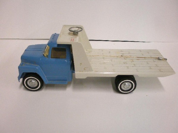 Ertl Die Cast Flatbed Tow Truck: 1973 Ertl die cast metal flatbed tow truck, date stamp Jan 9 1973 & numbered 6843-7102 on bottom. CONDITION: Glue & dirt residue, staining on flatbed & attached labels on back of truck.