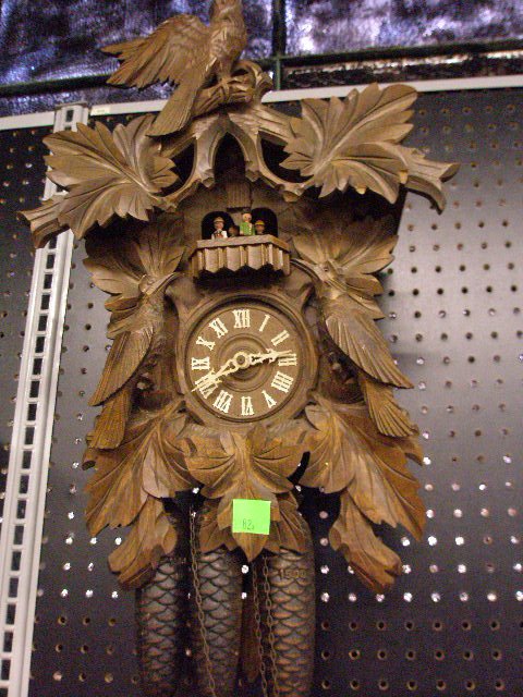 Black Forest Cuckoo Clock: Black Forest cuckoo clock, musical rotating figures on platform, bird & foliate carved walnut case, three weight, mid 20th C., 18" height.