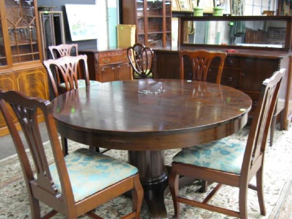 Empire-Style Dining Room Set: Eight piece mahogany dining room set, includes: six Chippendale-style arm chairs, center pedestal 54" diameter extension table w/six leaves & Sheraton-style mirrored back sideboard, early 20th C.