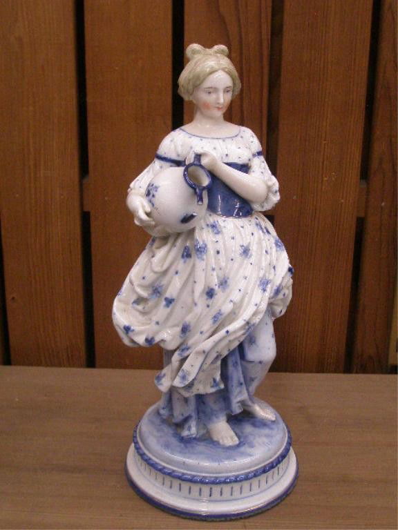 19th c. KPM Porcelain Figure: 19th c. KPM hand painted blue & white porcelain 10 1/2" figure, depicting a young girl w/vase in arm, standing against a tree stump base, opening on top of tree stump base for lamp mounting (portion m