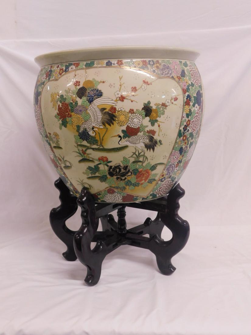 Chinese Porcelain Fish Bowl: Chinese Porcelain Fish Bowl, features panels of enameled cranes and flowers in life settings, elaborate multi colored floral borders, Koi fish painted interior, 14"h, 16 1/2"d, sets upon a fold up woo